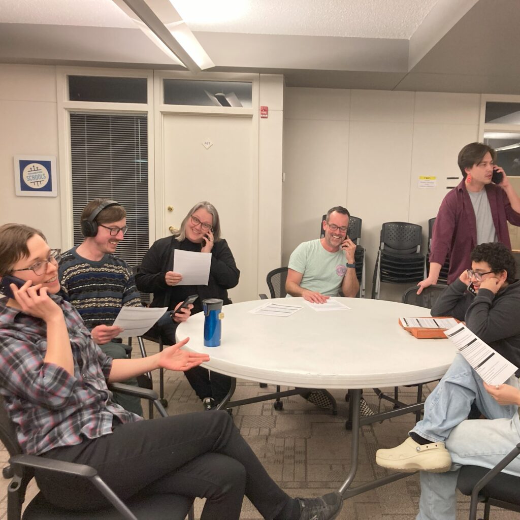 advocates gather around a table with phones and scripts for a phone bank